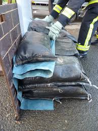 sandbag wall demonstration showing firefighter layering polythene sheeting with sandbags