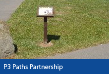 Public Footpaths button, small sign on pedestal in the grass on Braunton Village Green