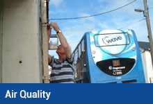 Air Quality button, Councillor changing tube for air quality monitoring in Caen Street Braunton as blue bus passes
