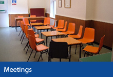 Meetings button, orange chairs around tables in the committee room